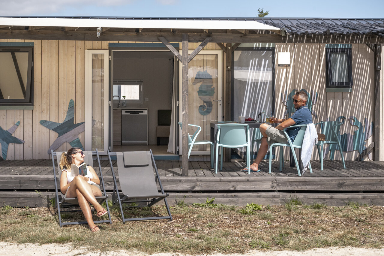 Couple relaxing on mobile home terrace, CLICOCHIC Etoile de Mer, Asserac (44).