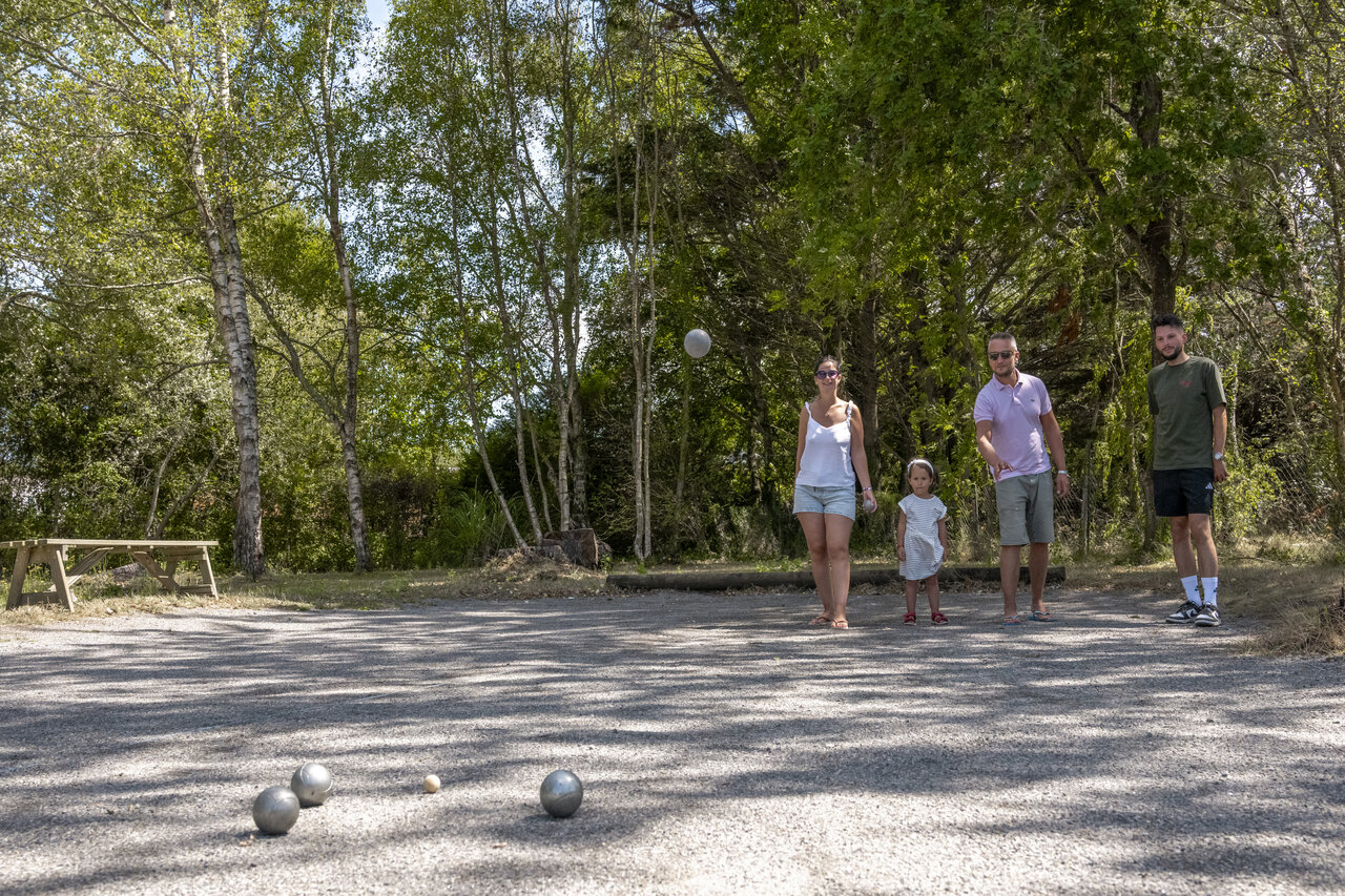 Family playing p�tanque on gravel court at CLICOCHIC Etoile de Mer camping.