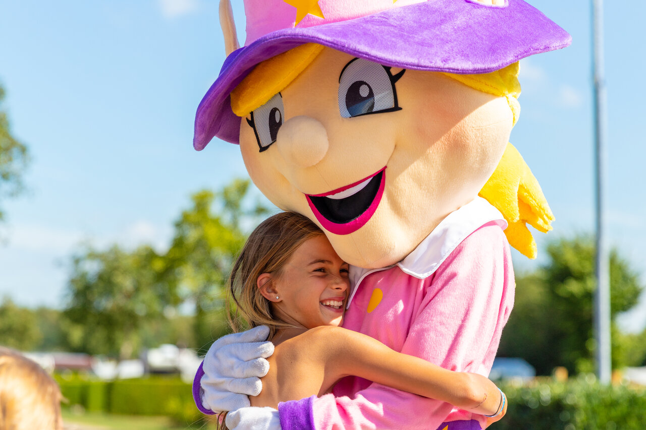 Smiling child hugging mascot at CAPFUN L'Eve campsite in Saint-Marc-sur-Mer.