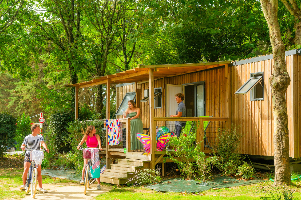 Wooden mobile home, terrace, young people with bikes at CAPFUN L'Eve (44).