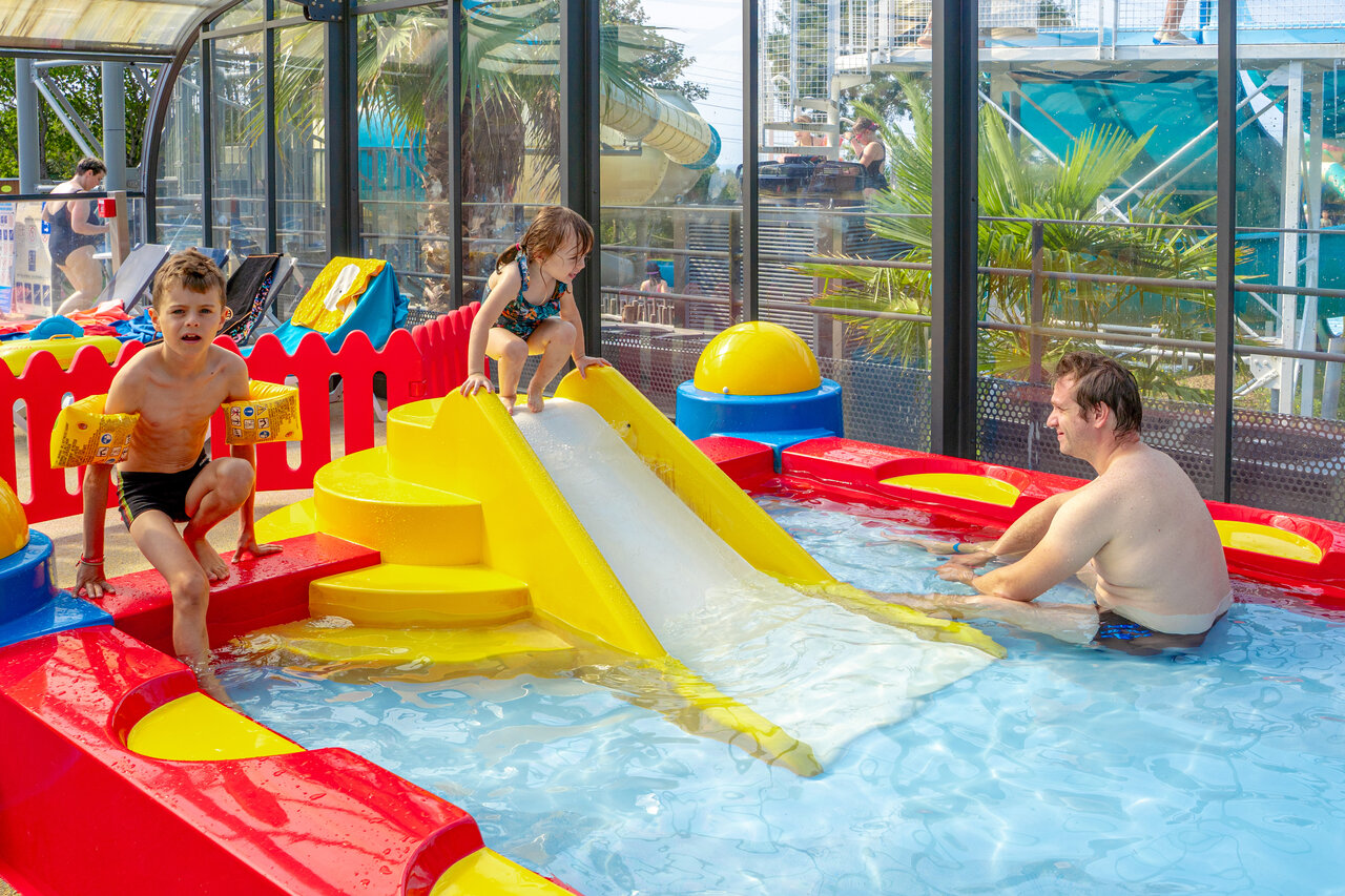 Indoor pool, slide and water games for children at CAPFUN L'Eve campsite.