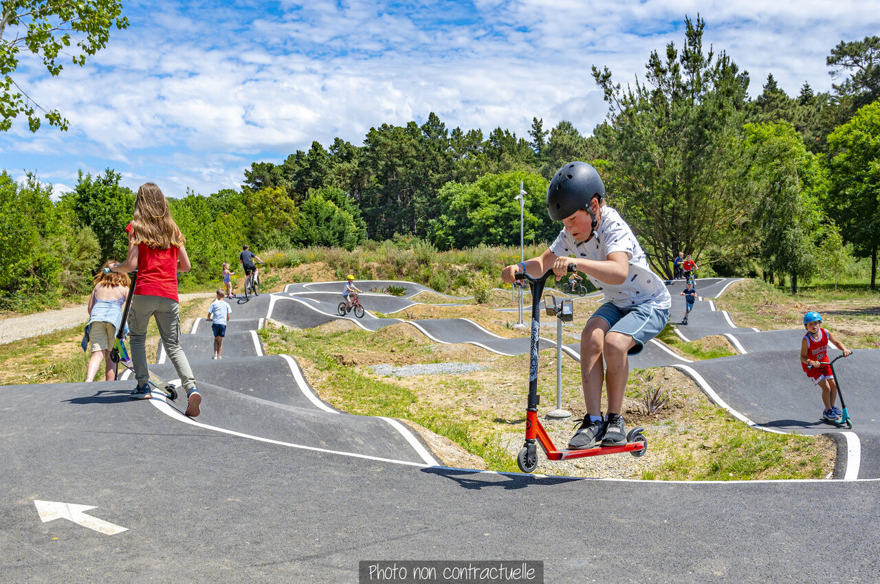Pump track with children on scooters and bikes at CAPFUN Falaises campsite in Gonneville sur Mer.
