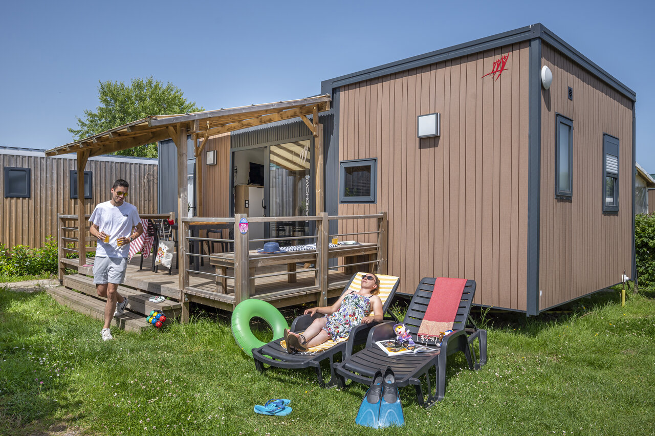 Modern mobile home with terrace, couple relaxing at CAPFUN Falaises campsite in Gonneville sur Mer (14).