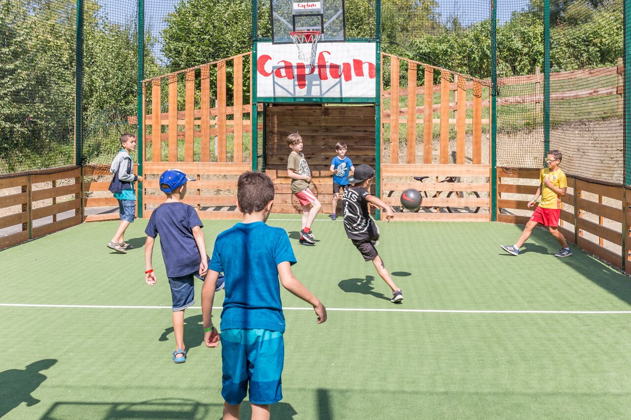 Multi-sport field with children playing ball at CAPFUN Falaises campsite in Gonneville sur Mer.