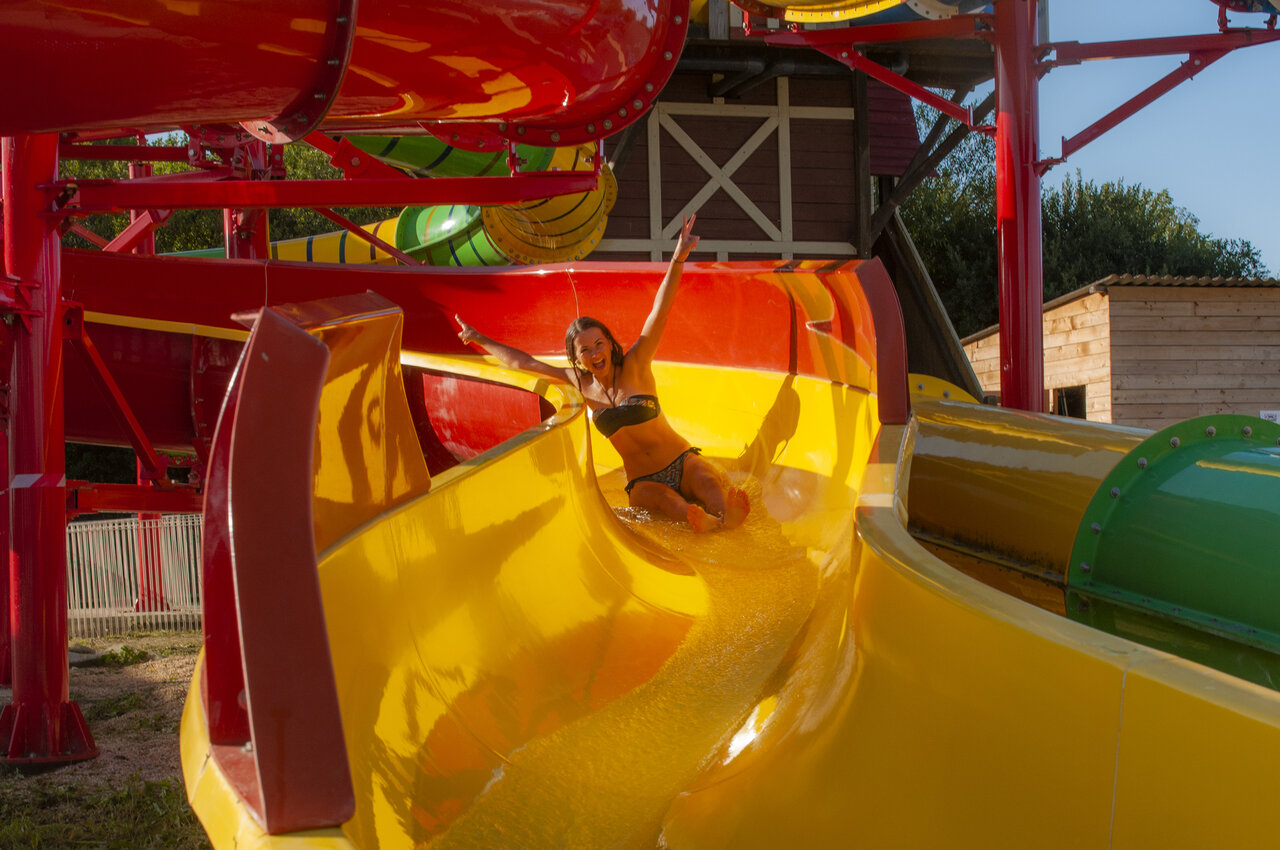 Smiling woman on water slide at CAPFUN Falaises campsite in Gonneville sur Mer.