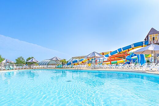 Outdoor swimming pool, water slides and chairs at CAPFUN Falaises campsite in Gonneville (14).