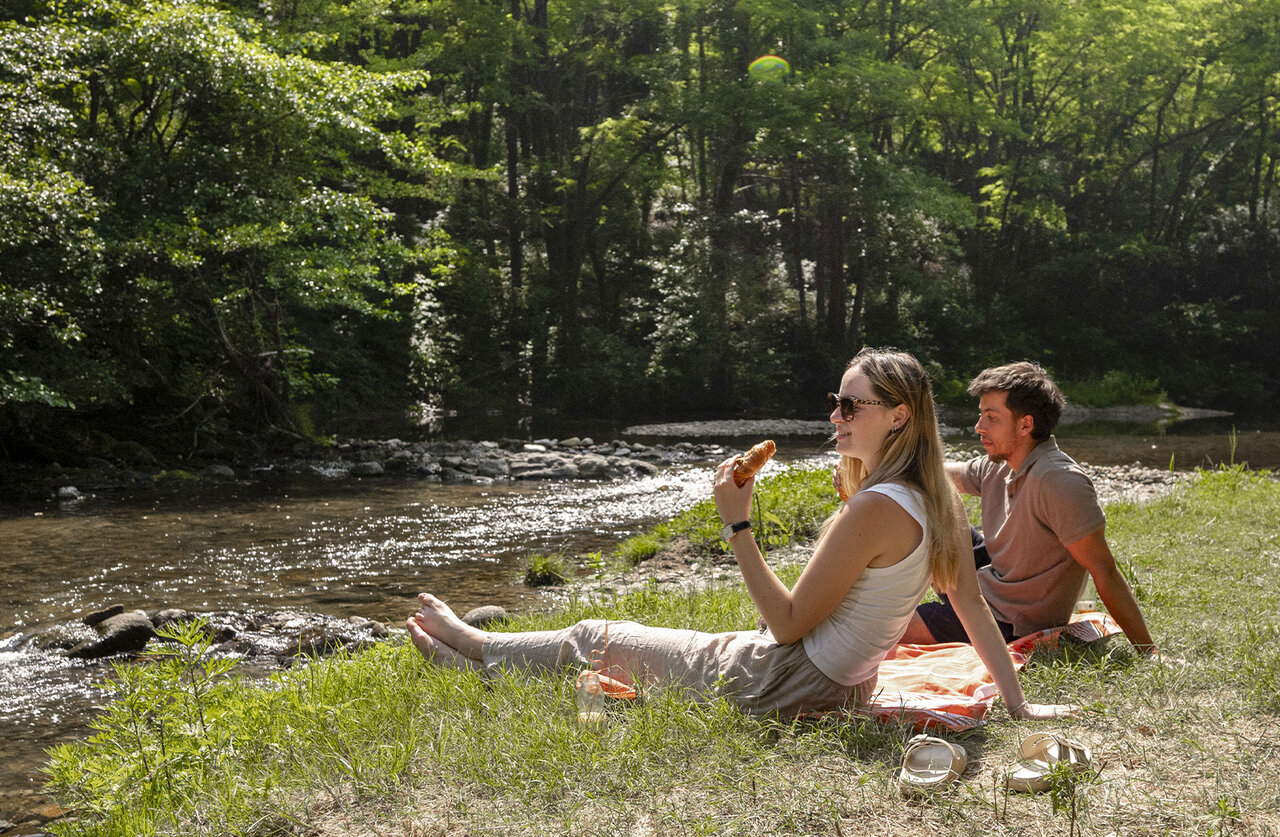 Couple picnicking river, greenery, at CLICOCHIC Filament campsite in Thoiras (30).
