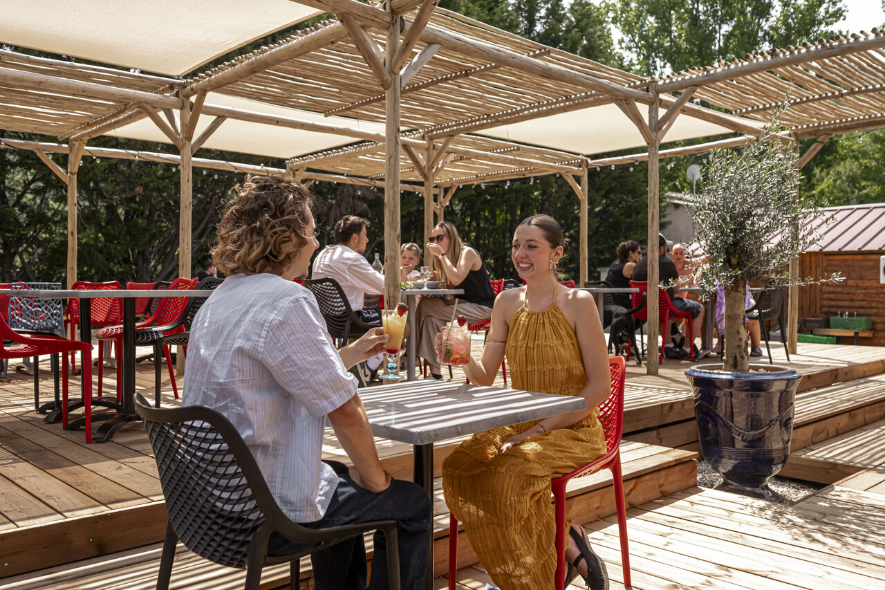 Bar and restaurant terrace, guests with cocktails at CLICOCHIC Filament campsite in Thoiras.