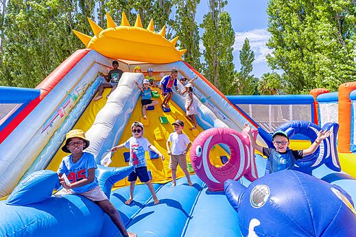Children playing on a large inflatable bouncy castle with slide at VAGUES OCEANES Au Flamenco campsite in Argel�s-sur-Mer (66).