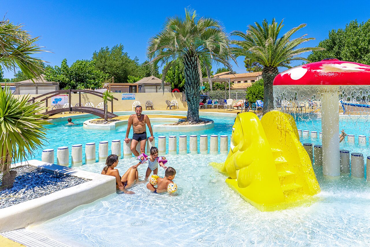 Outdoor pool, yellow slide and games at CAPFUN Flots Bleus campsite in VIAS PLAGE (34).