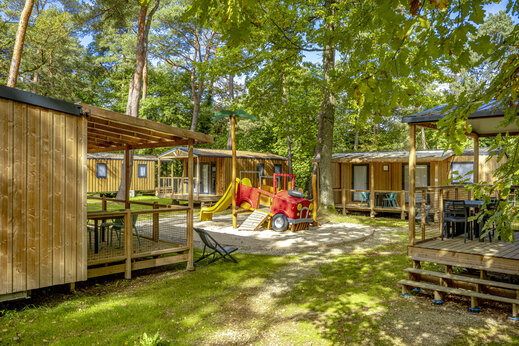 Wooden mobile homes and playground at camping CLICOCHIC La Forêt d'Azalée.