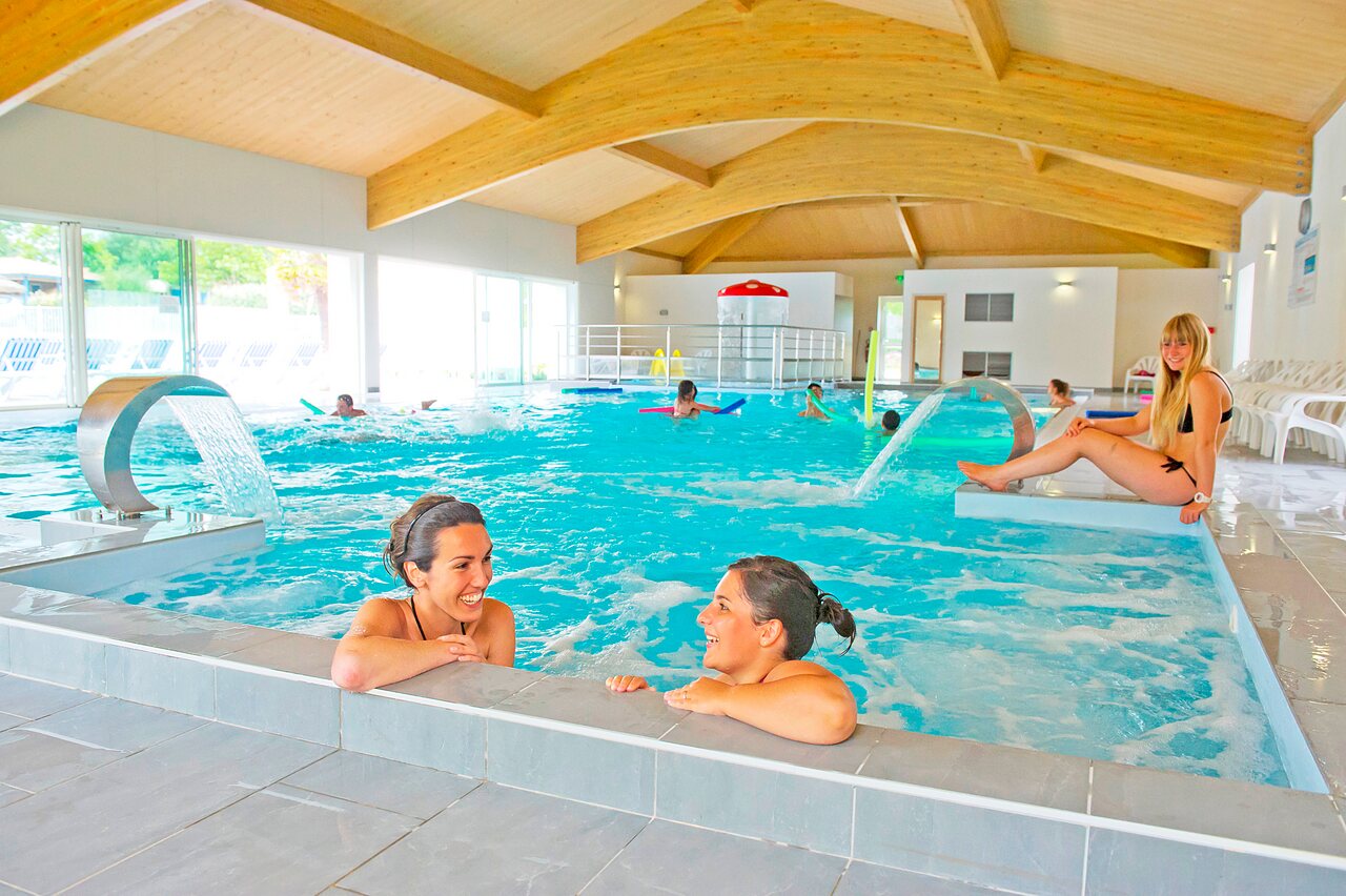 Heated indoor swimming pool with water jets and bathers at CAPFUN Forges campsite in Avrille (85).