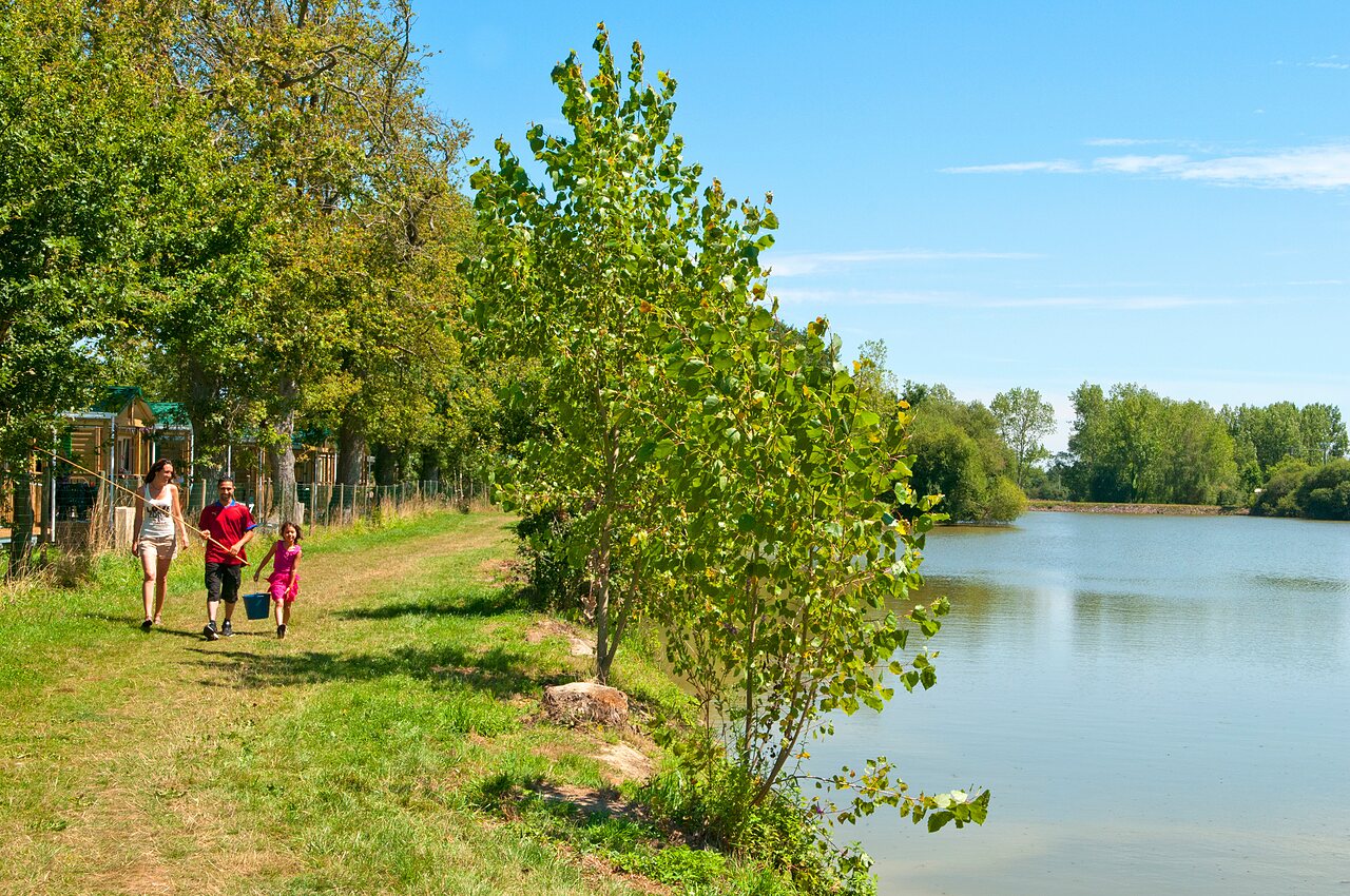Family fishing by the lake, accommodations in background at CAPFUN Forges campsite Avrille (85).