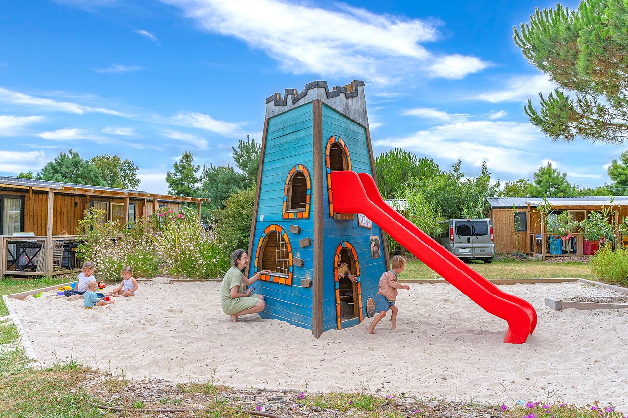 Playground with wooden tower, slide, and sandpit at CAPFUN Forges campsite in Avrille (85).