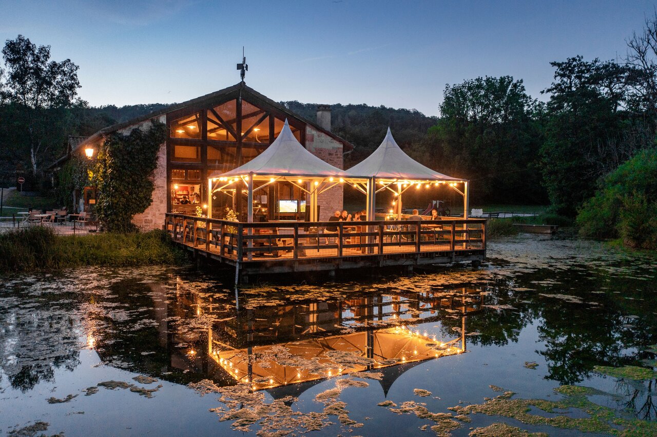 Illuminated restaurant and bar on deck at camping CLICOCHIC Forge Sainte Marie.