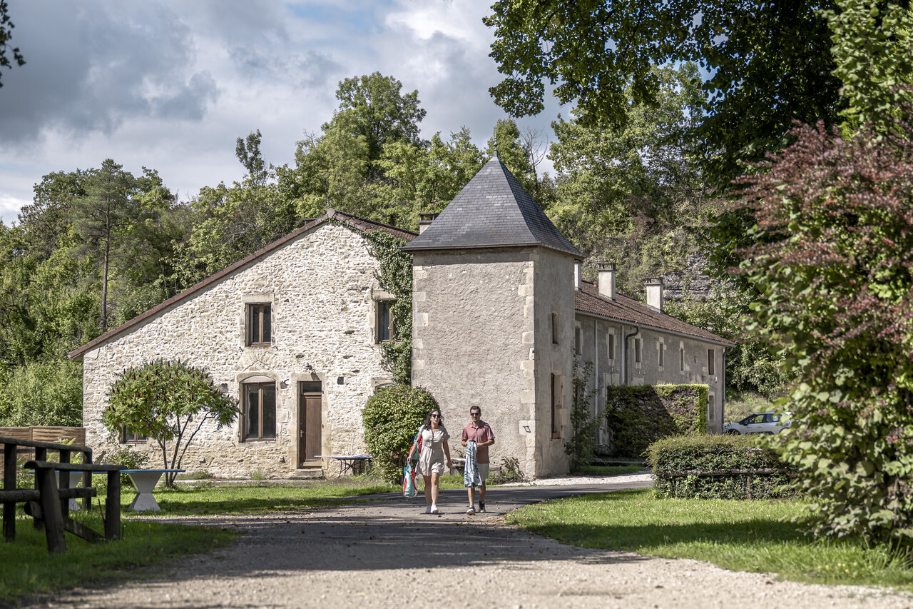Main stone building, couple on path at CLICOCHIC Forge Sainte Marie campsite.