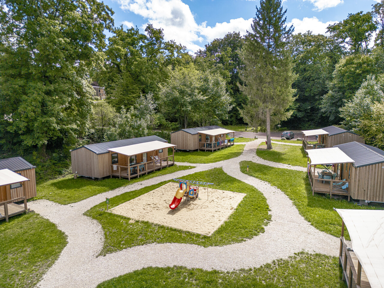 Wooden chalets, children's playground at CLICOCHIC Forge Sainte Marie campsite (52).
