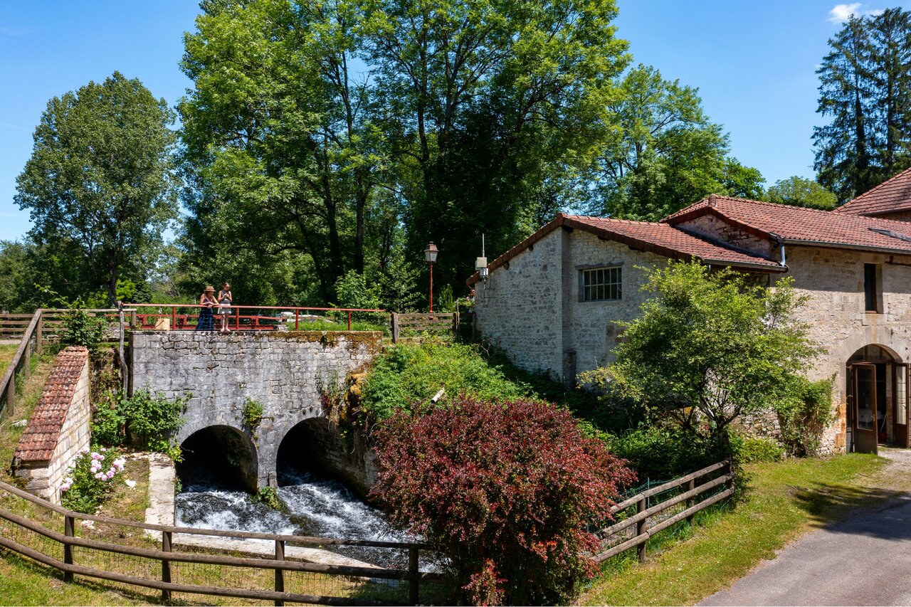River, stone bridge, old building at CLICOCHIC Forge Sainte Marie campsite.