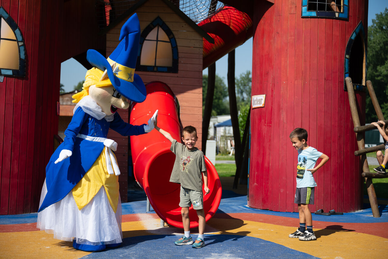 Mascot and children playing on the playground with slide at CAPFUN Fort Bedmar campsite in Sint-Gillis-Waas.