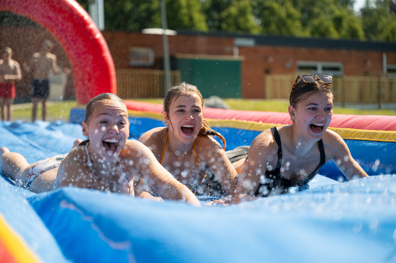 Smiling girls on inflatable water slide at CAPFUN Fort Bedmar campsite in Sint-Gillis-Waas.