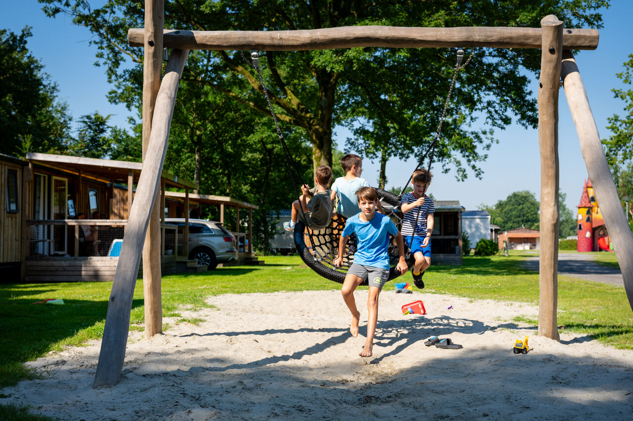 Children playing on a nest swing, playground at CAPFUN Fort Bedmar campsite.