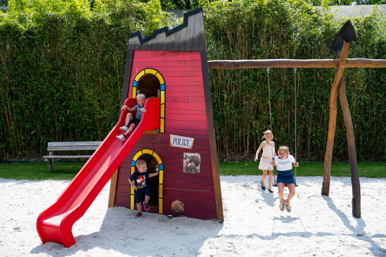 Playground with slide and swings for children at CAPFUN Fort Bedmar campsite in Sint-Gillis-Waas.