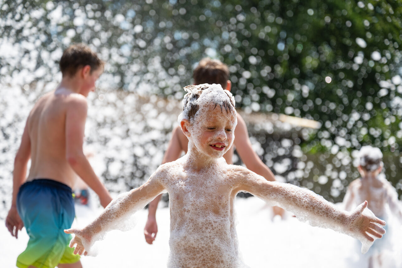 Happy children playing in a foam party at CAPFUN Fort Bedmar campsite in Sint-Gillis-Waas.