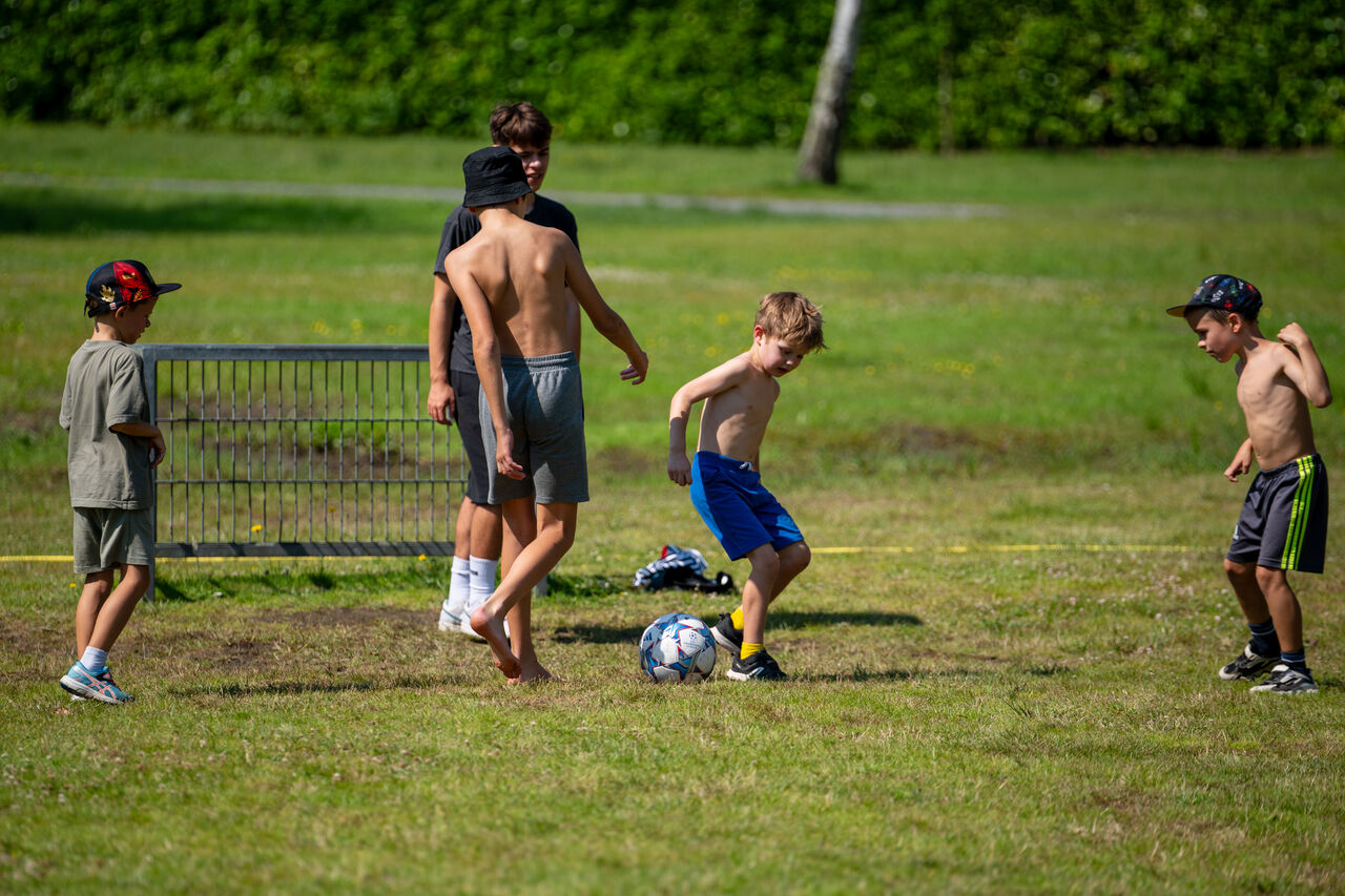 Children playing football on a sports field at CAPFUN Fort Bedmar campsite in Sint-Gillis-Waas.