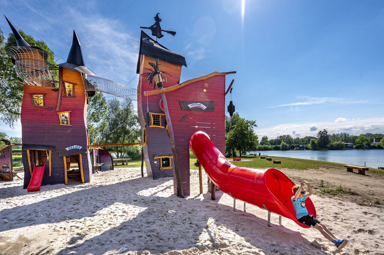Red slide, themed playground on sand at CAPFUN Fort Falabraque Seltz.
