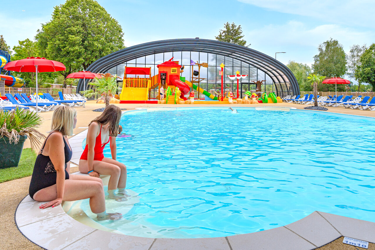 Two women by the pool with water games at CAPFUN Fort Falabraque campsite in Seltz (67).