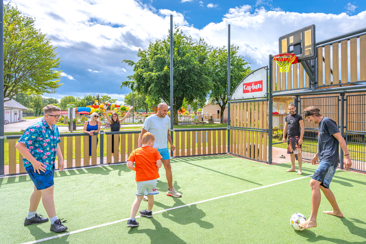 Multi-sport court with family playing football and basketball at CAPFUN Fort Falabraque campsite in Seltz (67).