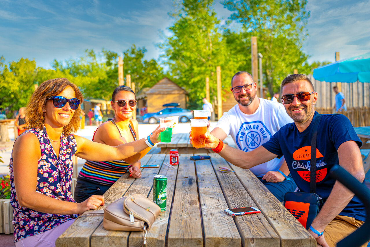 Friends toasting at the outdoor bar of CAPFUN Fort Falabraque campsite in Seltz (67).