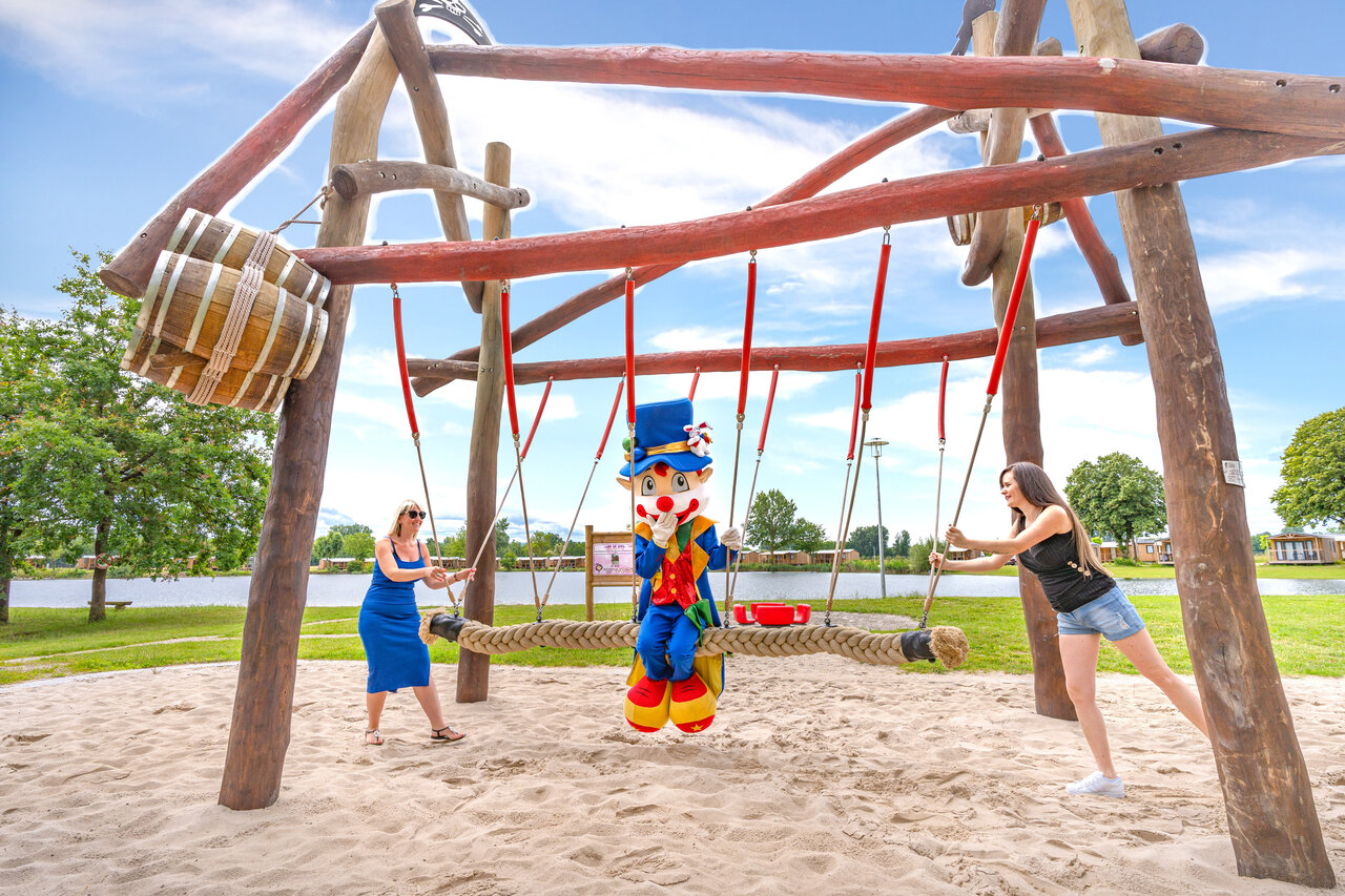Mascot and women on swing at CAPFUN Fort Falabraque campsite in Seltz (67).