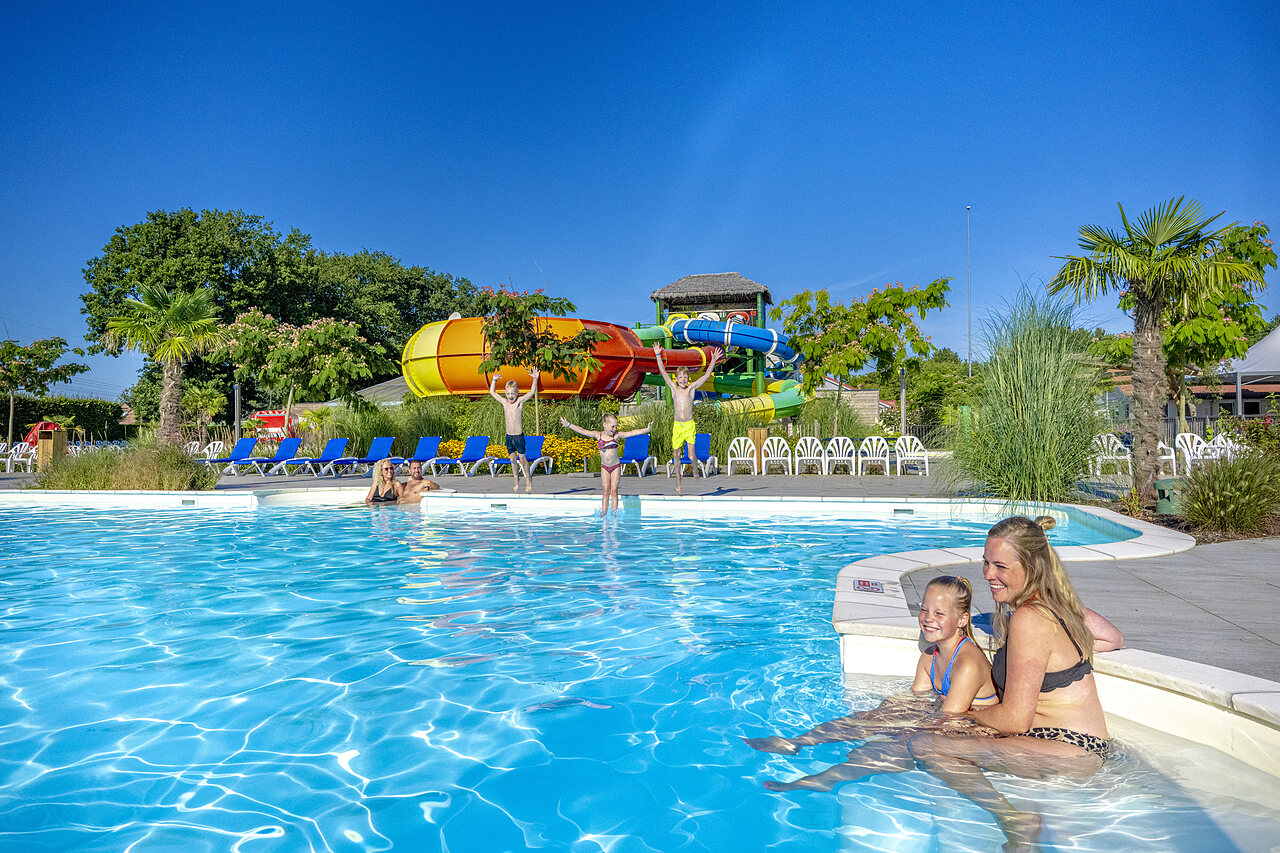 Outdoor swimming pool with water slides and happy family at CAPFUN De Fruithof campsite in Klijndijk.