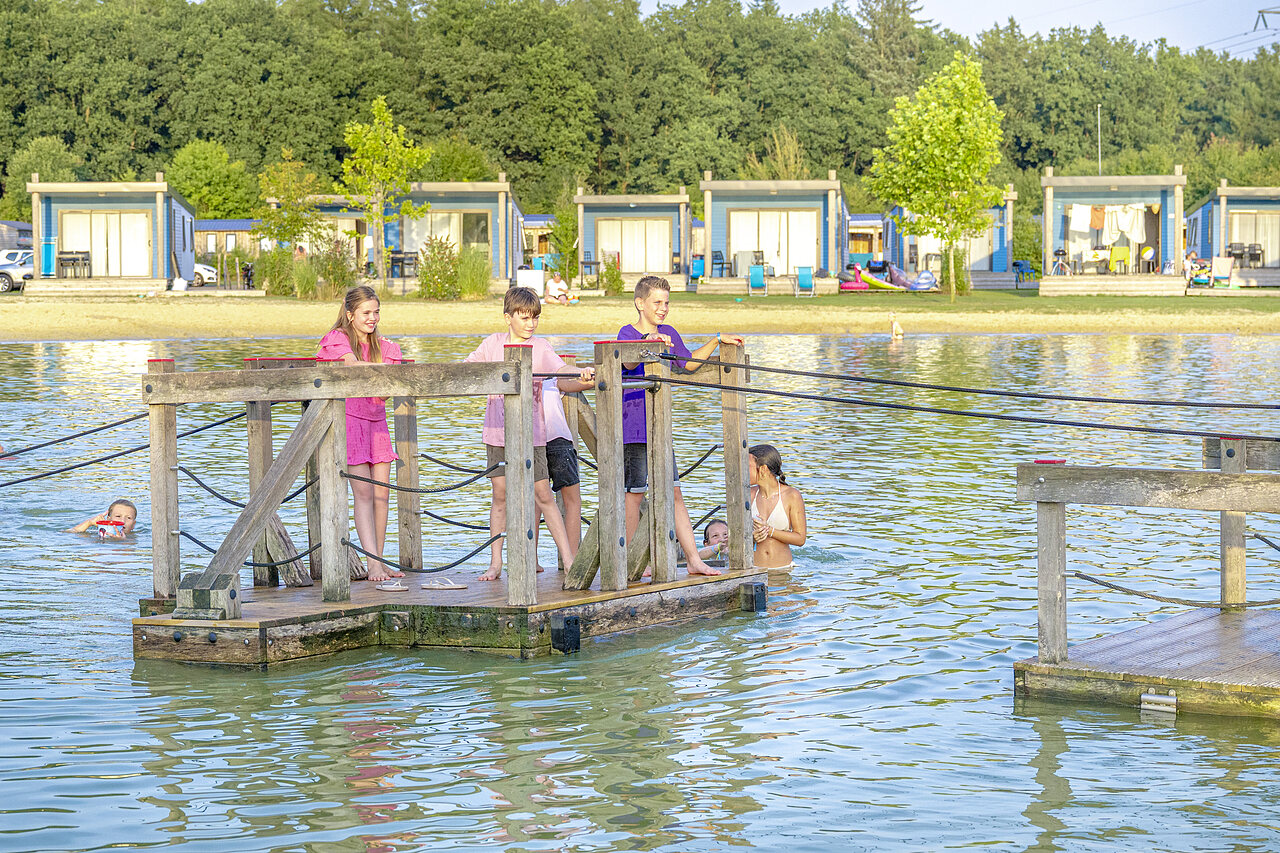 Children playing on floating platform in lake, accommodations at CAPFUN De Fruithof campsite in Klijndijk.