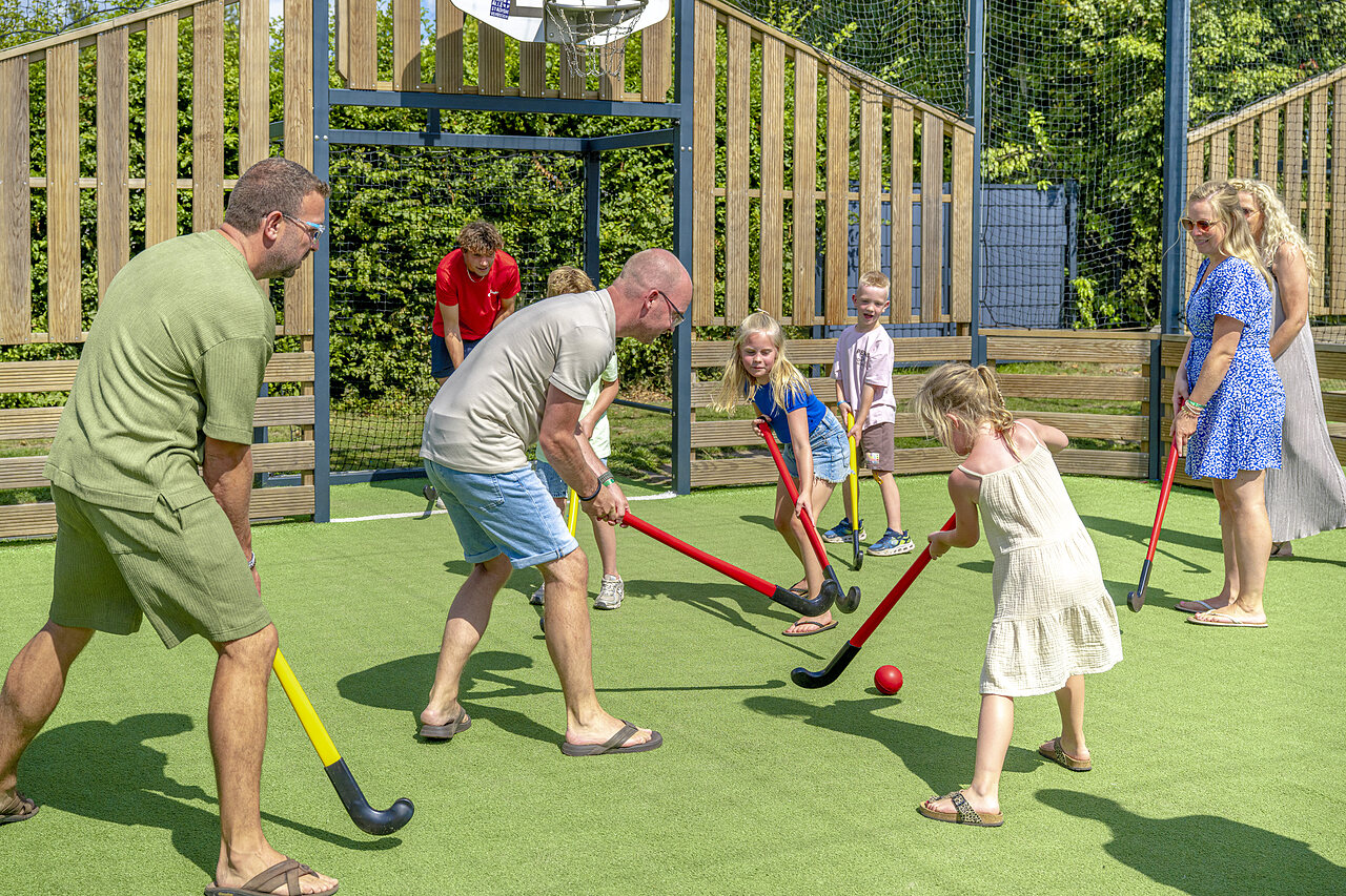 Family playing field hockey on artificial turf at CAPFUN De Fruithof campsite in Klijndijk.