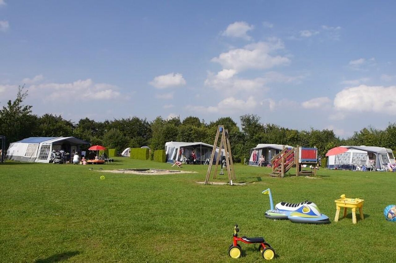 Green camping pitches with children's playground at CAPFUN De Fruithof campsite in Klijndijk.