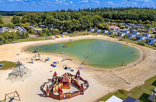 Swimming pond, sandy beach and playground at CAPFUN De Fruithof campsite in Klijndijk.