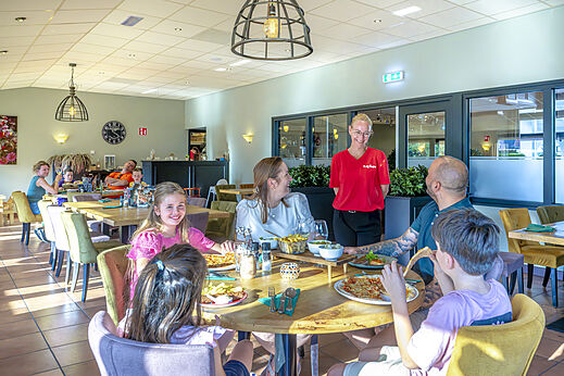 Family happily dining at the restaurant of camping CAPFUN De Fruithof in Klijndijk.