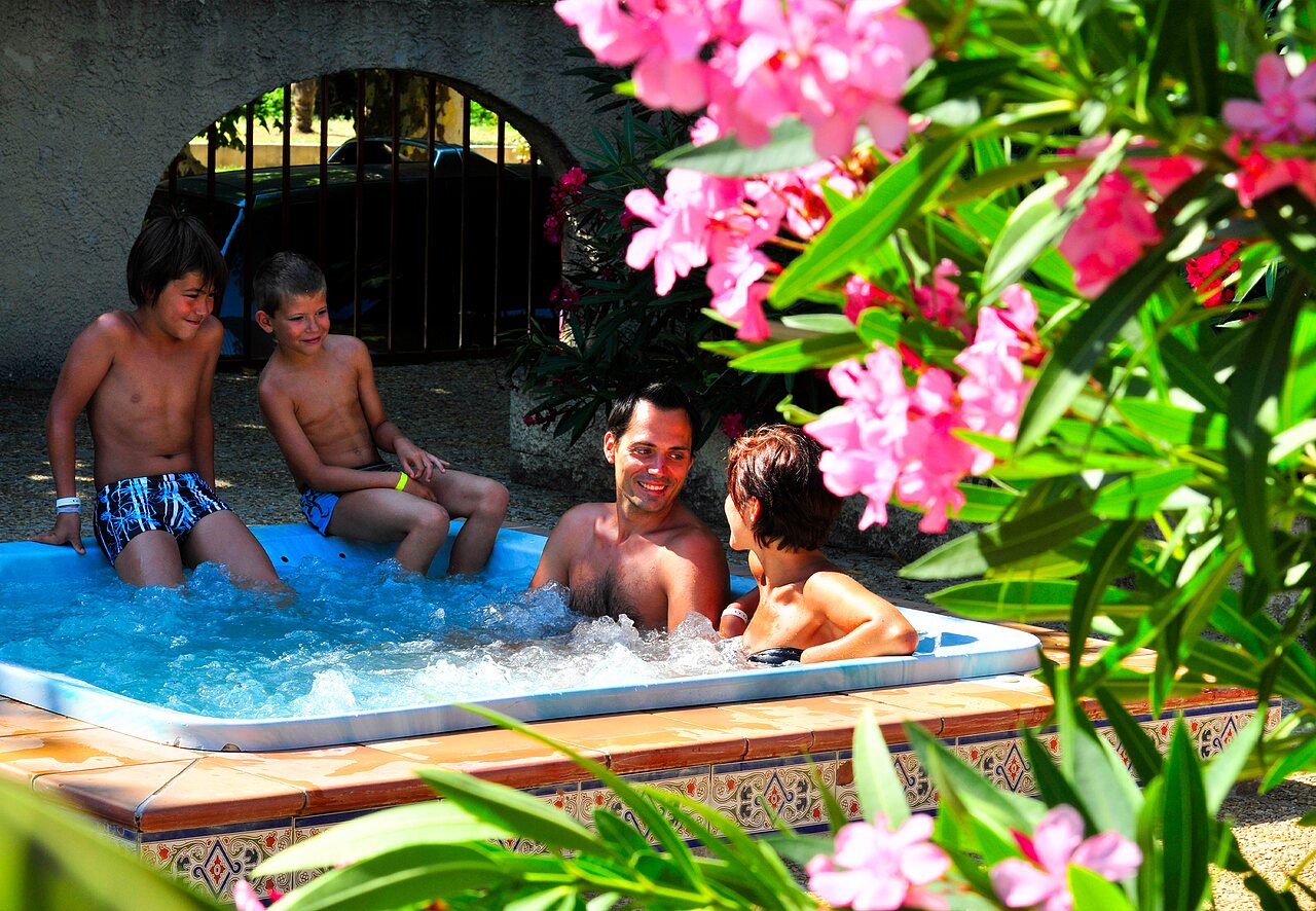 Smiling family enjoying bubbling hot tub at CAPFUN Fumades campsite in ALLEGRE-LES-FUMADES (30).