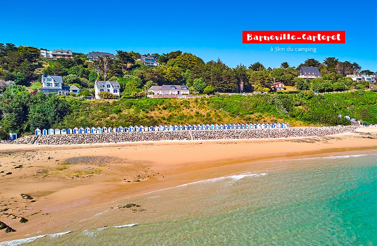 Barneville-Carteret beach with colorful beach huts and houses on the Normandy coast.