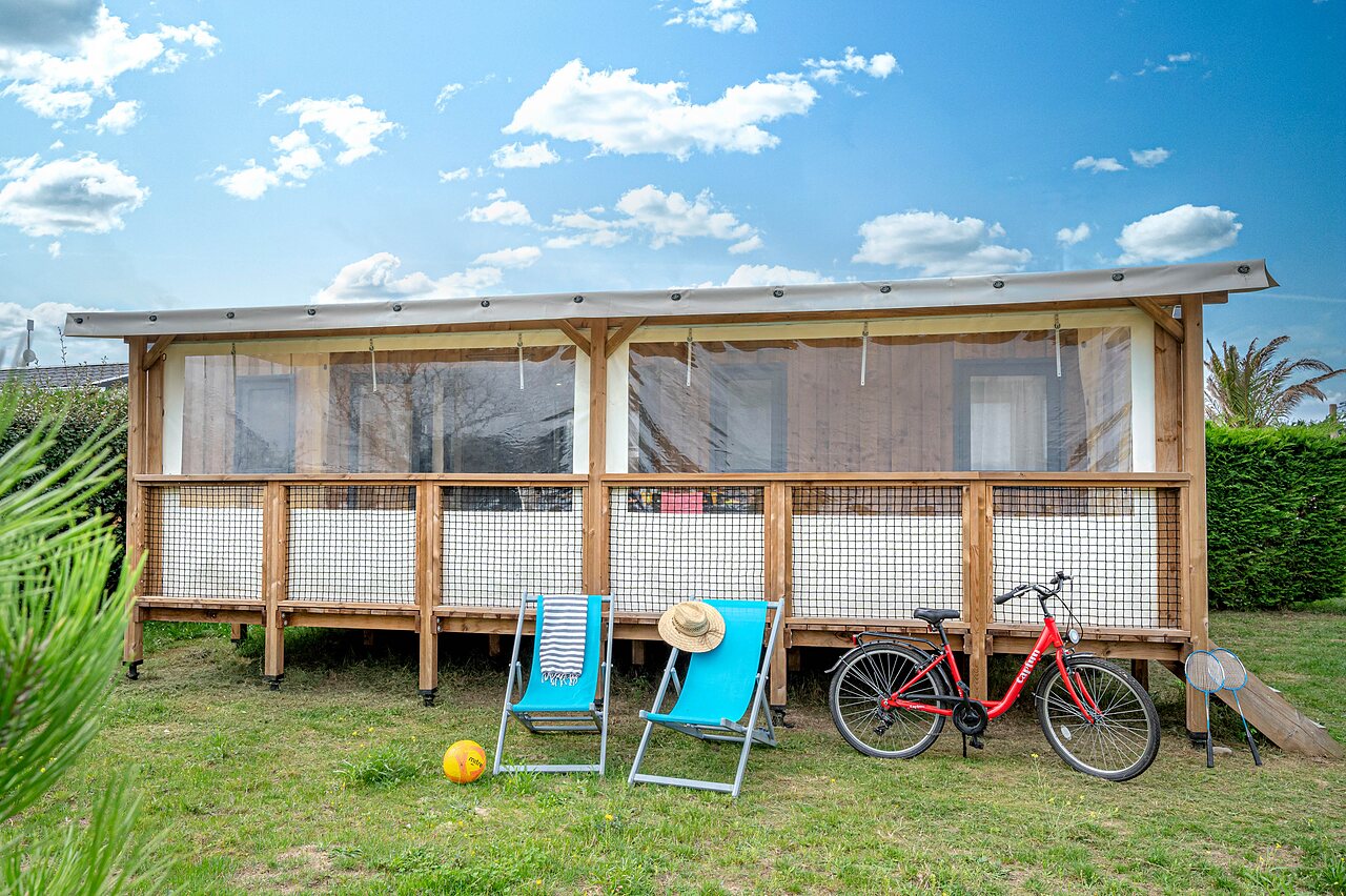 Glamping lodge, deck chairs, bicycle at CAPFUN Golf campsite in SAINT JEAN DE LA RIVIERE (50).