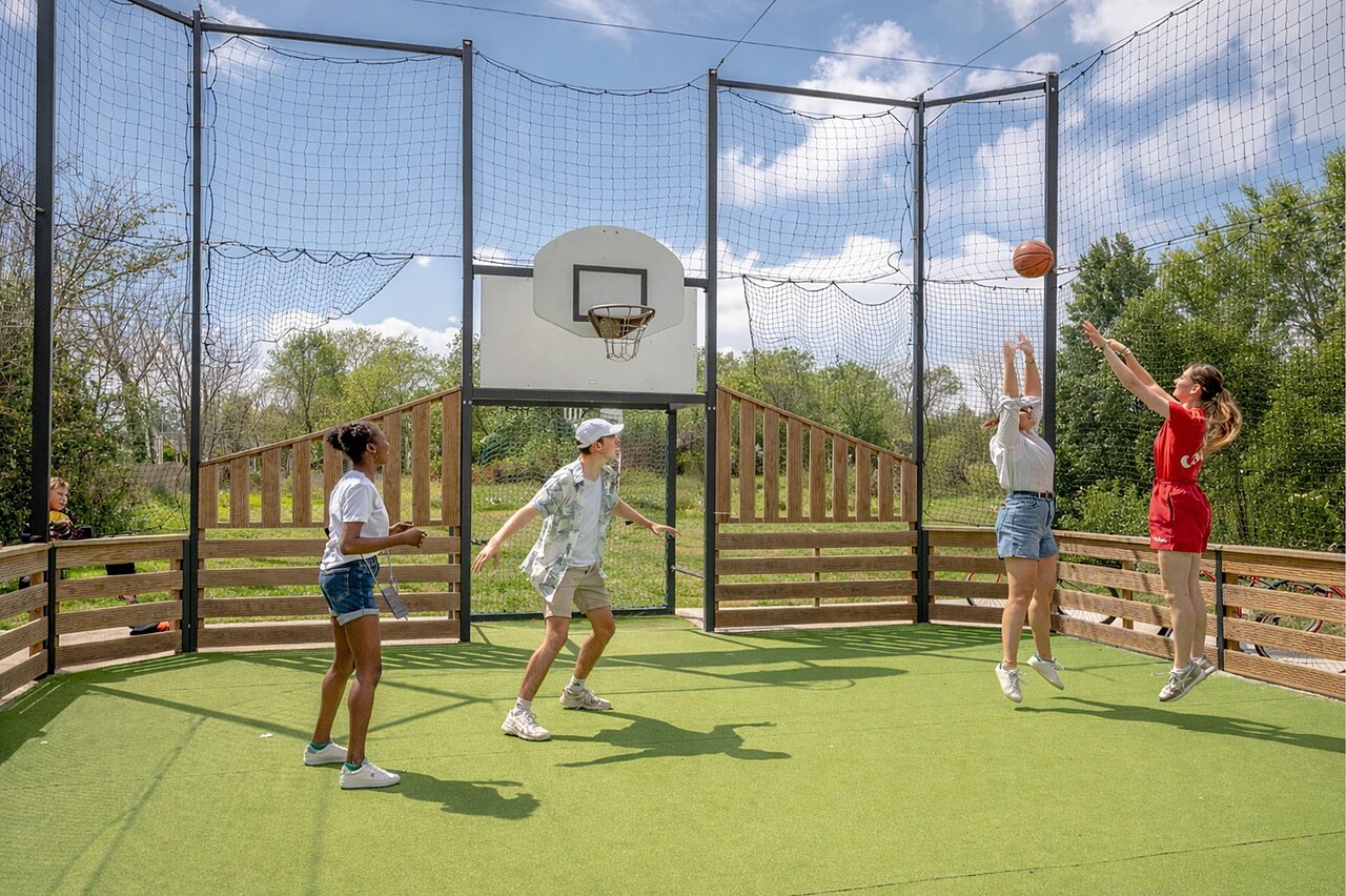 Multisport court with young people playing basketball at CAPFUN Golf campsite in SAINT JEAN DE LA RIVIERE (50).