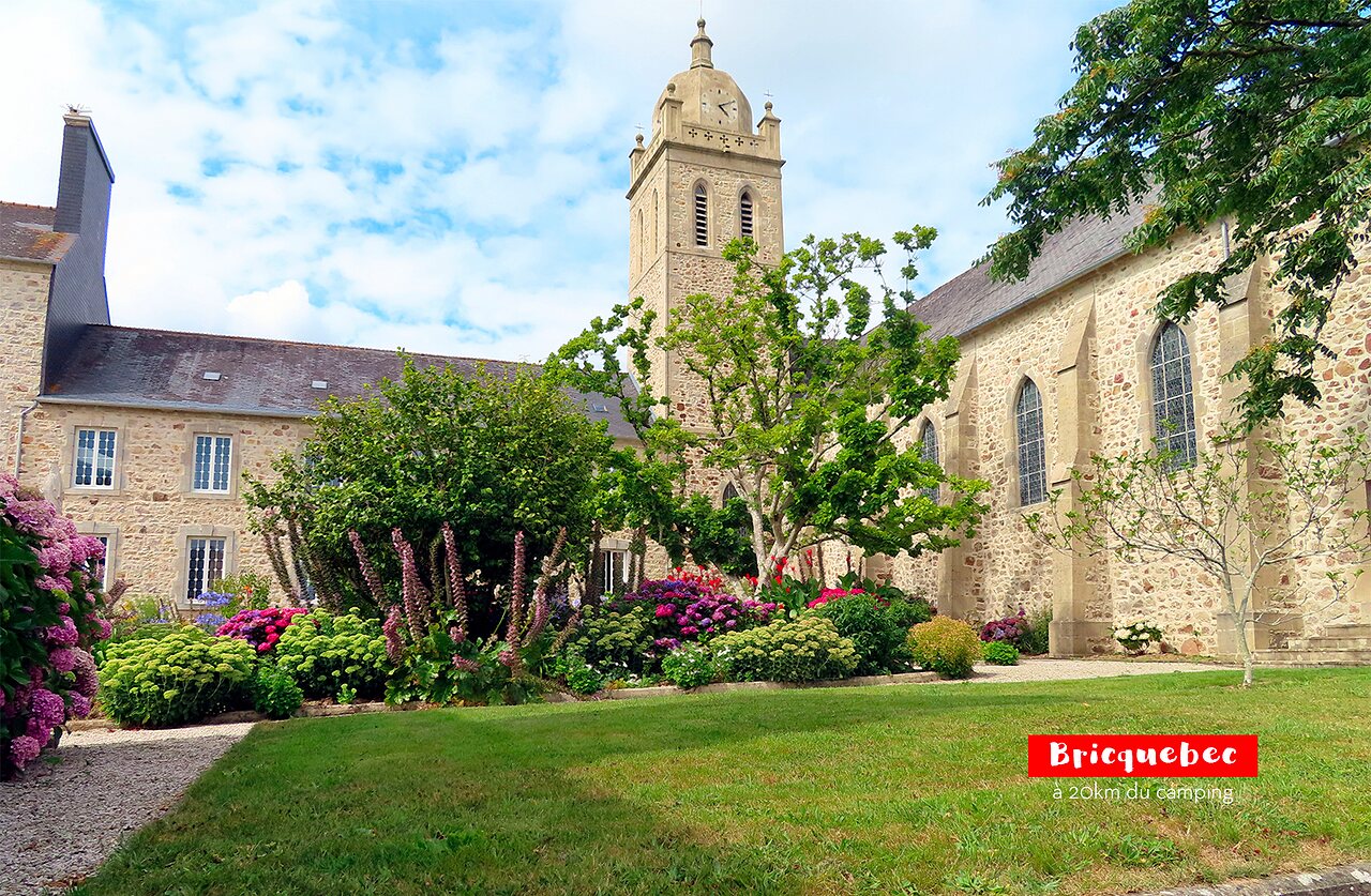 Historic Bricquebec church with bell tower and flowered garden, to visit in Normandy.
