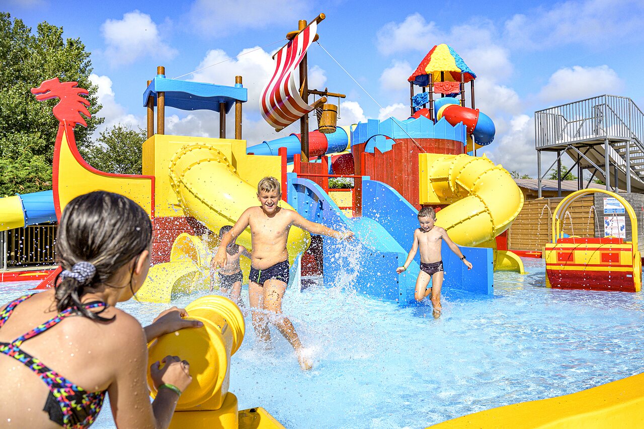 Water park with slides, water games and happy children at CAPFUN Golf campsite in SAINT JEAN DE LA RIVIERE (50).