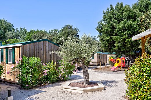 Wooden mobile homes and playground at CLICOCHIC Gorges du Gardon campsite in VERS PONT DU GARD (30).