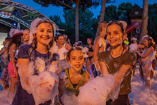 Smiling children enjoying an animated foam party at CLICOCHIC Gorges du Gardon campsite in VERS PONT DU GARD (30).