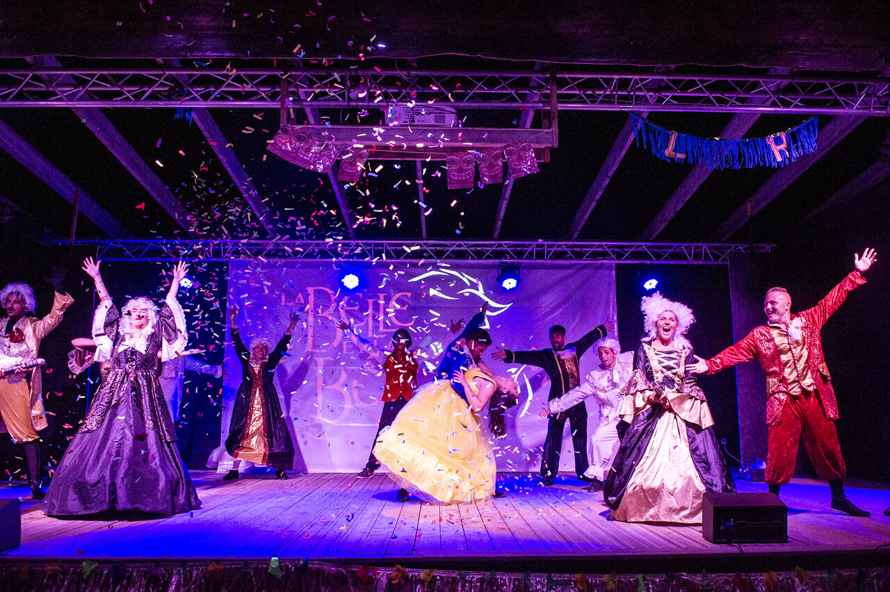 Costumed dancers performing with confetti on stage at CAPFUN Grande Cosse campsite.