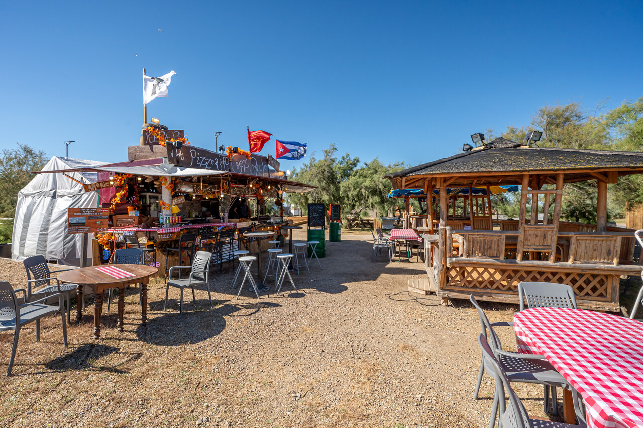 Outdoor pizzeria restaurant with tables and chairs at CAPFUN Grande Cosse campsite in Saint Pierre la Mer (11).