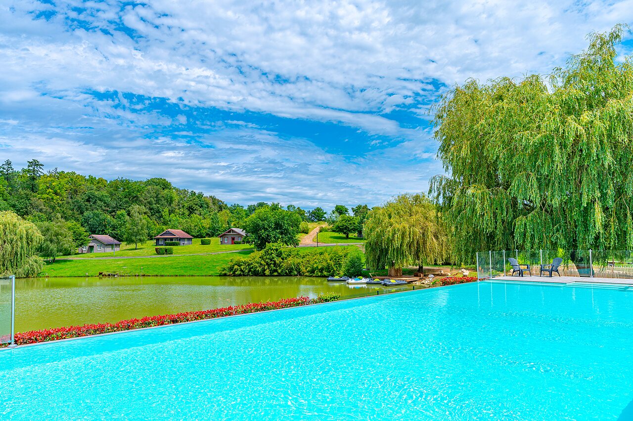 Infinity pool, lake, and chalets at CAPFUN Grand Cerf campsite in Gimouille (58).
